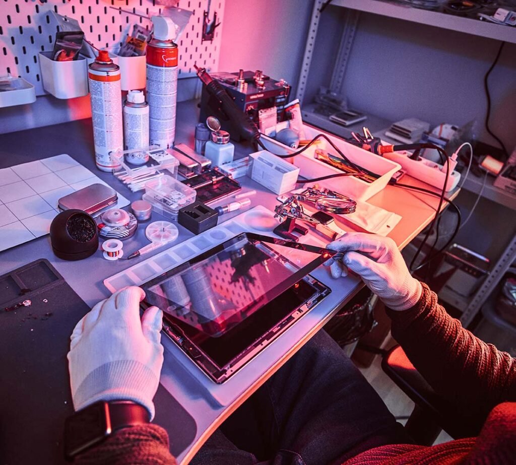 Escritorio con herramientas y teléfonos, persona trabajando en reparación electrónica.